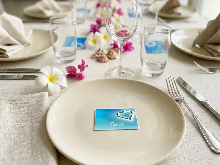Table d'honneur de mariage avec marque-places sur le thème des îles tropicales et de la mer, fleurs de tiaré et verres