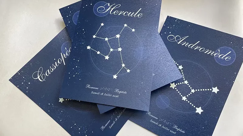 Un carton de table affichant la constellation Hercule posé sur d'autres cartes de constellations