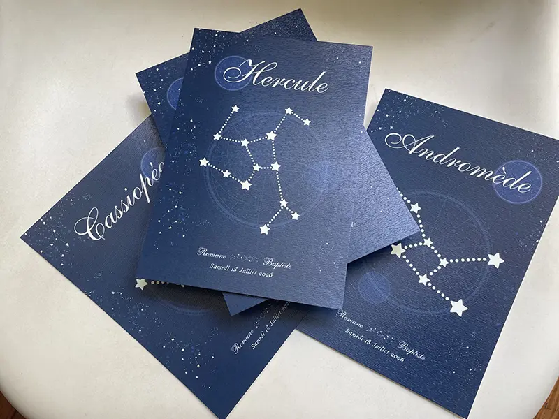 Un carton de table affichant la constellation Hercule posé sur d'autres cartes de constellations